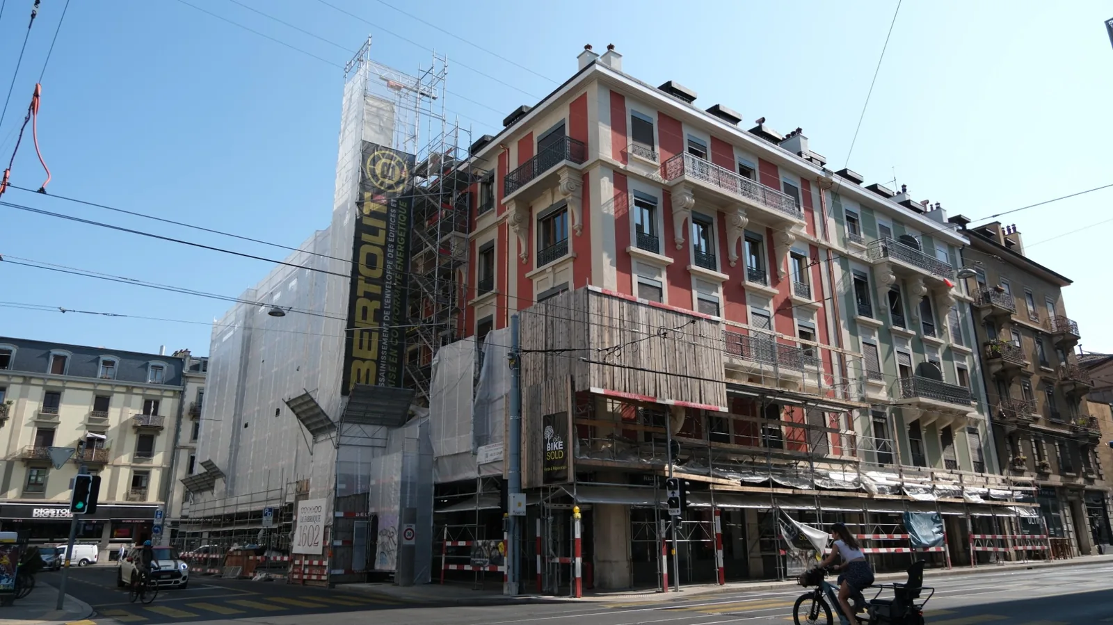 Façade genevoise en rénovation au crépi isolant à l'aérogel, échafaudage bâché Bertolit le long d'une ligne de tram